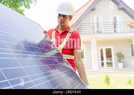 Techniker trägt Solarmodul vor dem Haus Stockfoto