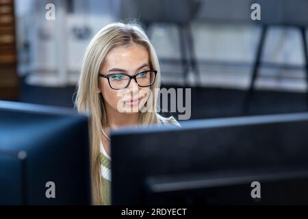Junge Geschäftsfrau mit Brille, die am Computer arbeitet Stockfoto