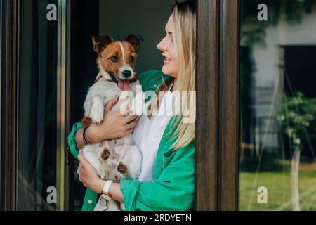 Eine Frau, die einen Hund an der Tür hält Stockfoto