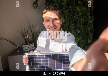 Glücklicher Geschäftsmann, der Selfie mit Solarmodul im Büro macht Stockfoto