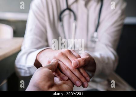 Arzt, der die Hand des Patienten in der Klinik hält Stockfoto