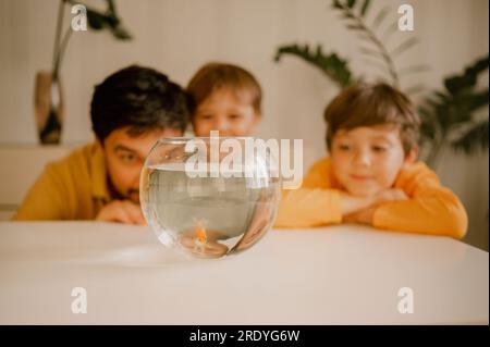 Vater mit Kindern, der Fisch in der Schüssel ansieht Stockfoto