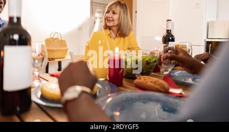 Lächelnde Seniorin, die mit Freunden zu Hause zu Abend isst Stockfoto