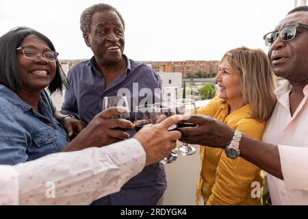 Glückliche Freunde, die auf dem Balkon Getränke toasten Stockfoto