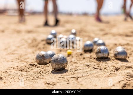 Petanque-Bälle im Sand am Meer während eines Spiels am Strand. Stockfoto