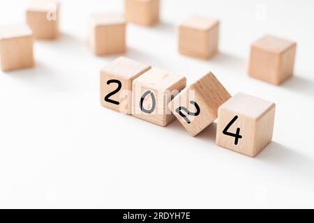 Holzwürfel aus Buche mit der Aufschrift 2023, die sich in einen weißen 2024-Hintergrund verwandelt Stockfoto