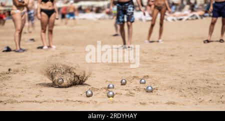 Petanque-Bälle im Sand am Meer während eines Spiels am Strand. Stockfoto