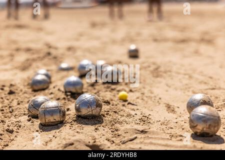 Petanque-Bälle im Sand am Meer während eines Spiels am Strand. Stockfoto