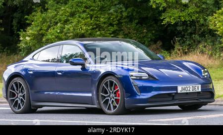 Milton Keynes, Großbritannien - Juli 21. 2023: 2022 blauer Porsche Taycan 4S 93KWH Elektroauto, das auf einer englischen Straße fährt Stockfoto