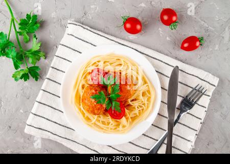 Traditionelle Fleischbällchen in schmackhafter Tomatensauce, serviert mit Pasta, Tomaten und Petersilie Stockfoto