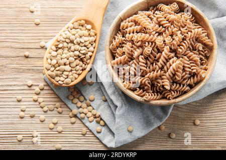 Grüne Linsenfusilli-Pasta auf altem Holzhintergrund. Eine Schüssel mit roher Pasta und grünen Linsen. Glutenfreie Pasta. Stockfoto