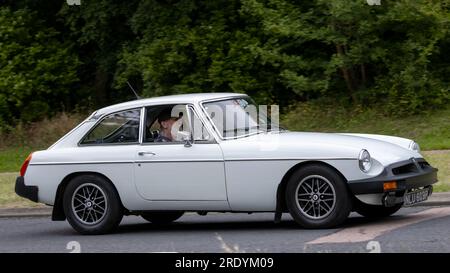 Milton Keynes, Großbritannien - Juli 21. 2023: 1976 weißer MG B GT Sportwagen, der auf einer englischen Straße fährt Stockfoto