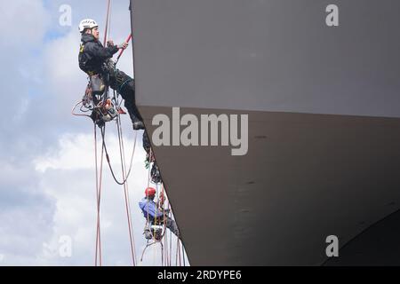 PRODUKTION - 20. Juli 2023, Hamburg: Industrieklieger Marlon Dirchs (l) reinigt ein Fenster der Konzerthalle Elbphilharmonie im Hafen. Mehrmals im Jahr kommt ein Team furchtloser Kletterer in Hamburg an, um der berühmtesten Konzerthalle der Stadt einen neuen Glanz zu verleihen. Die Glasfassade der Hamburger Elbphilharmonie hat eine Fläche von etwa 16.000 Quadratmetern. Dreimal im Jahr werden die 1100 unterschiedlich geformten Fenster und Glaselemente von professionellen Kletterern gereinigt. Foto: Marcus Brandt/dpa Stockfoto