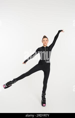 Springstiefel, weißer Hintergrund, Sportlerin in schwarzem Overall und kangoo-Springschuhe Stockfoto