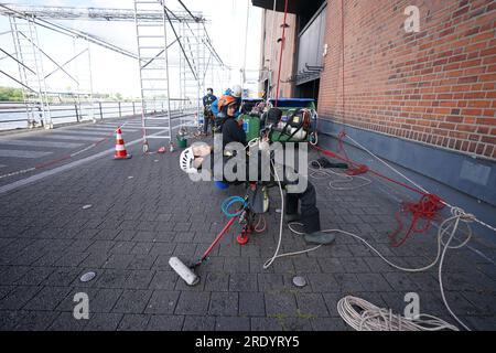 PRODUKTION – 20. Juli 2023, Hamburg: Industrieklieger Marlon Dirchs (Front) und sein Team bereiten sich auf die Fensterreinigung in der Konzerthalle Elbphilharmonie im Hafen vor. Mehrmals im Jahr kommt ein Team furchtloser Kletterer in Hamburg an, um der berühmtesten Konzerthalle der Stadt einen neuen Glanz zu verleihen. Die Glasfassade der Elbphilharmonie in Hamburg erstreckt sich über eine Fläche von etwa 16.000 Quadratmetern. Dreimal im Jahr werden die 1100 unterschiedlich geformten Fenster und Glaselemente von professionellen Kletterern gereinigt. Foto: Marcus Brandt/dpa Stockfoto