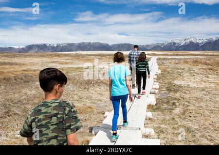 Vater und drei Kinder gehen auf einem bewachten Pfad in die Berge Stockfoto