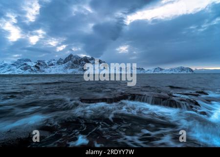 Wolken auf Wellen schlagen auf Felsen, Vareid, Flakstad, Norwegen Stockfoto