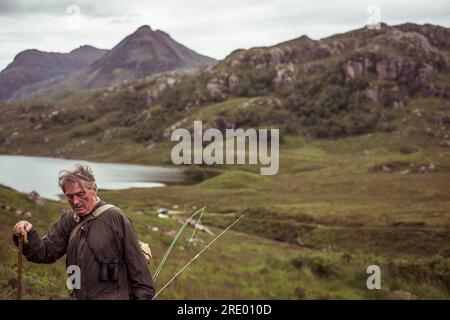 Ein Rentner klettert auf einem Angelausflug in schottland auf den Berg über loch Stockfoto