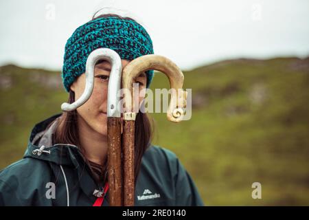 Mädchen schaut durch Wanderstöcke in den Bergen Stockfoto