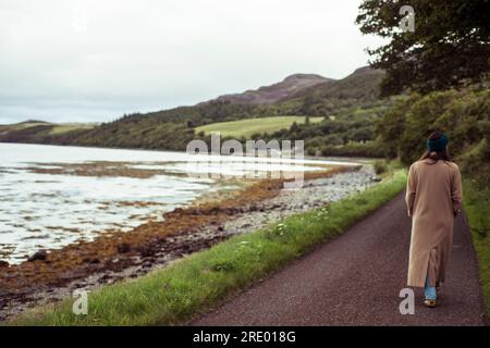 Rückansicht einer Person, die auf einem kleinen Pfad um den See in den Bergen spaziert Stockfoto