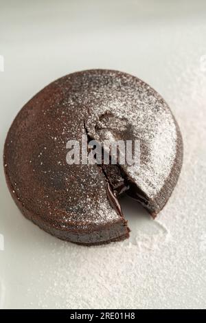 Schokoladensoufflé mit fließender Schokolade auf einem weißen Porzellanteller Stockfoto