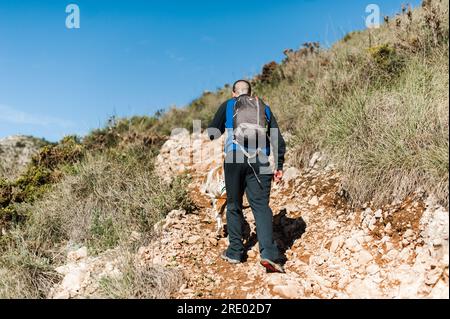 Junger Mann, der in Malaga, Spanien, bergauf wandert, gegen den blauen Himmel Stockfoto