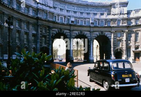 Schwarzes Taxi vor Admiralty Arch mit Blick auf die Mall zum Buckingham Palace, London, England, Großbritannien. Etwa 1980er Jahre Stockfoto