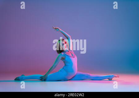 Schwangere Frau, die Beinspalten-Dehnungsübungen in Neon macht Stockfoto