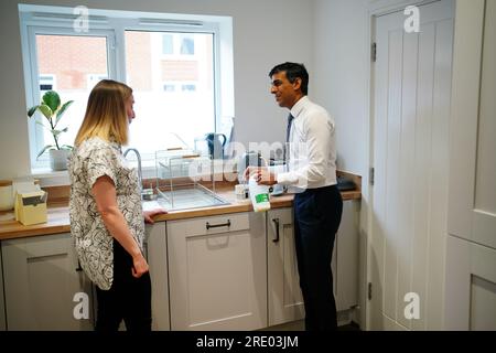 Premierministerin Rishi Sunak spricht mit der Hausbesitzerin Jennifer Norton, die bei einem Besuch im Cofton Park in der Nähe von Rednal, Birmingham, zu Hause eine Tasse Tee in einer Tasse Nummer 10 macht. Foto: Montag, 24. Juli 2023. Stockfoto