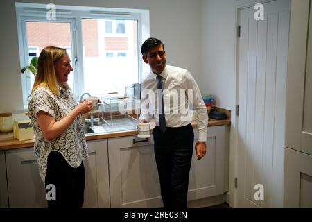 Premierministerin Rishi Sunak spricht mit der Hausbesitzerin Jennifer Norton, die bei einem Besuch im Cofton Park in der Nähe von Rednal, Birmingham, eine Tasse Tee in einer Tasse Nummer 10 in ihrem Haus trinkt. Foto: Montag, 24. Juli 2023. Stockfoto