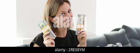 Eine Frau, die auf der Couch sitzt, zeigt eine Menge Geld Stockfoto