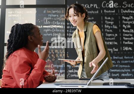 Schüler mit Tablet-pc, der während DES IT-Unterrichts mit einem Lehrer im Klassenzimmer spricht Stockfoto