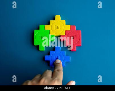 Personensymbol auf Puzzleblöcken verschiedene Farben werden zusammengestellt und von Hand auf blauem Hintergrund vervollständigt. Geschäftspartnerschaft, Personalwesen, Teamgeist Stockfoto