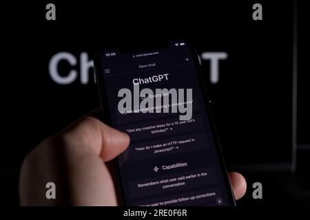 Azoren, Portugal - 21.01.2023: Smartphone-Handheld-ChatGPT-Prompt-Webseite und im Hintergrund verschwommenes ChatGPT-Wortkabel auf einem Laptop-Bildschirm. Stockfoto