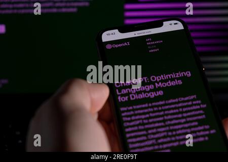 Azoren, Portugal - 21.01.2023: Smartphone-Handheld-ChatGPT-Prompt-Webseite und im Hintergrund verschwommenes ChatGPT-Wortkabel auf einem Laptop-Bildschirm. Stockfoto