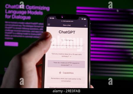 Azoren, Portugal - 21.01.2023: Smartphone-Handheld-ChatGPT-Prompt-Webseite und im Hintergrund verschwommenes ChatGPT-Wortkabel auf einem Laptop-Bildschirm. Stockfoto