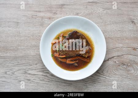 Gedünstetes Hähnchenschenkel und Bein mit Karotten in Sojasoße auf dem Teller Stockfoto