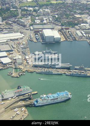 Blick aus der Vogelperspektive auf den Marinestützpunkt seiner Majestät, Portsmouth (HMNB Portsmouth) mit Kriegsschiffen und HMS Ark Royal Flugzeugträger sowie Fähren Stockfoto