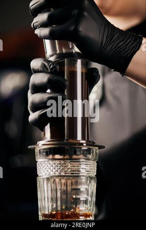 Teilansicht des Baristas, der Kaffee in der Aero Press presst, während er Espresso mit einer anderen Methode zubereitet Stockfoto