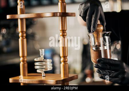 Teilansicht des Baristas, der Espresso zubereitet und Kaffee mit Manipulation in der Kaffeemaschine für kalten Kaffee presst Stockfoto