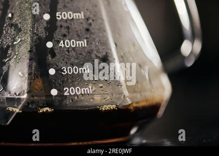 Nahaufnahme von schwarzem, frisch gebrühtem Espresso in einer Kaffeekanne aus Glas mit Messskala und Tropfmethode Stockfoto