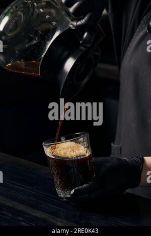 Der Barista gießt aromatischen Espresso aus der Kaffeekanne in Kristallglas, alternative Brühmethode Stockfoto