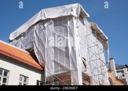 Gerüste mit Schutzlappen um ein Gebäude, um zu verhindern, dass Baumaterial während der Renovierung auf die Straße und auf Menschen fällt Stockfoto