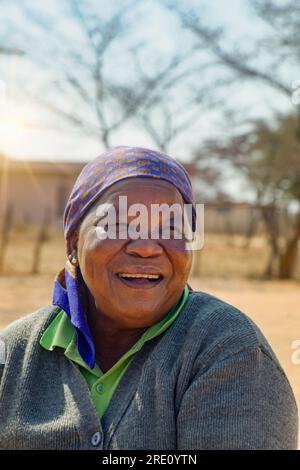 Dorfleben, sonniger Tag, alte afrikanische Frau im Hof, die aus dem Herzen lacht Stockfoto