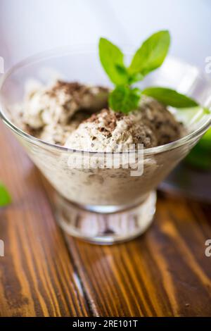 Hausgemachtes Eis mit Stücken geriebener dunkler Schokolade, in einer Schüssel auf einem Holztisch. Stockfoto