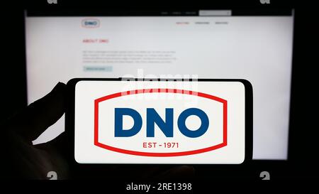 Person, die ein Smartphone mit dem Logo des norwegischen Öl- und Gasunternehmens DNO ASA auf dem Bildschirm vor der Website hält. Konzentrieren Sie sich auf das Display des Telefons. Stockfoto