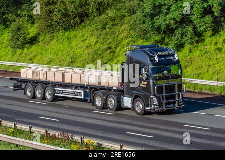 L Jukes Shropshire Express-Lieferungen. Cargo and Freight Flachbett Dennison Trailer & 2014 Volvo Globetrotter mit Betongusssteinblöcken; Fahrt mit hoher Geschwindigkeit auf der Autobahn M6 im Großraum Manchester, Großbritannien Stockfoto