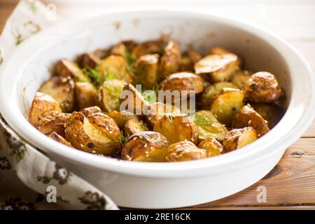 Kartoffeln, die mit Sesamsamen, Kräutern und Gewürzen im Ofen in keramischer Form gebacken wurden. Stockfoto