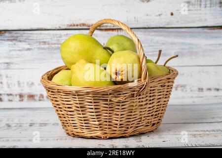 Frische Birnen in einem Korb aus Weidenholz auf Holzhintergrund. Konzept der Birnenernte. Gesundes und frisches Obst Stockfoto