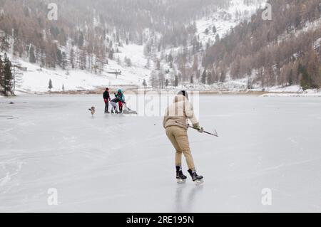 Villar Saint Pancrace (Südostfrankreich): Schlittschuhlaufen auf einem gefrorenen See im Winter. Leute, die Eishockey auf dem gefrorenen Lake Orceyrette spielen. Junger Mann Stockfoto